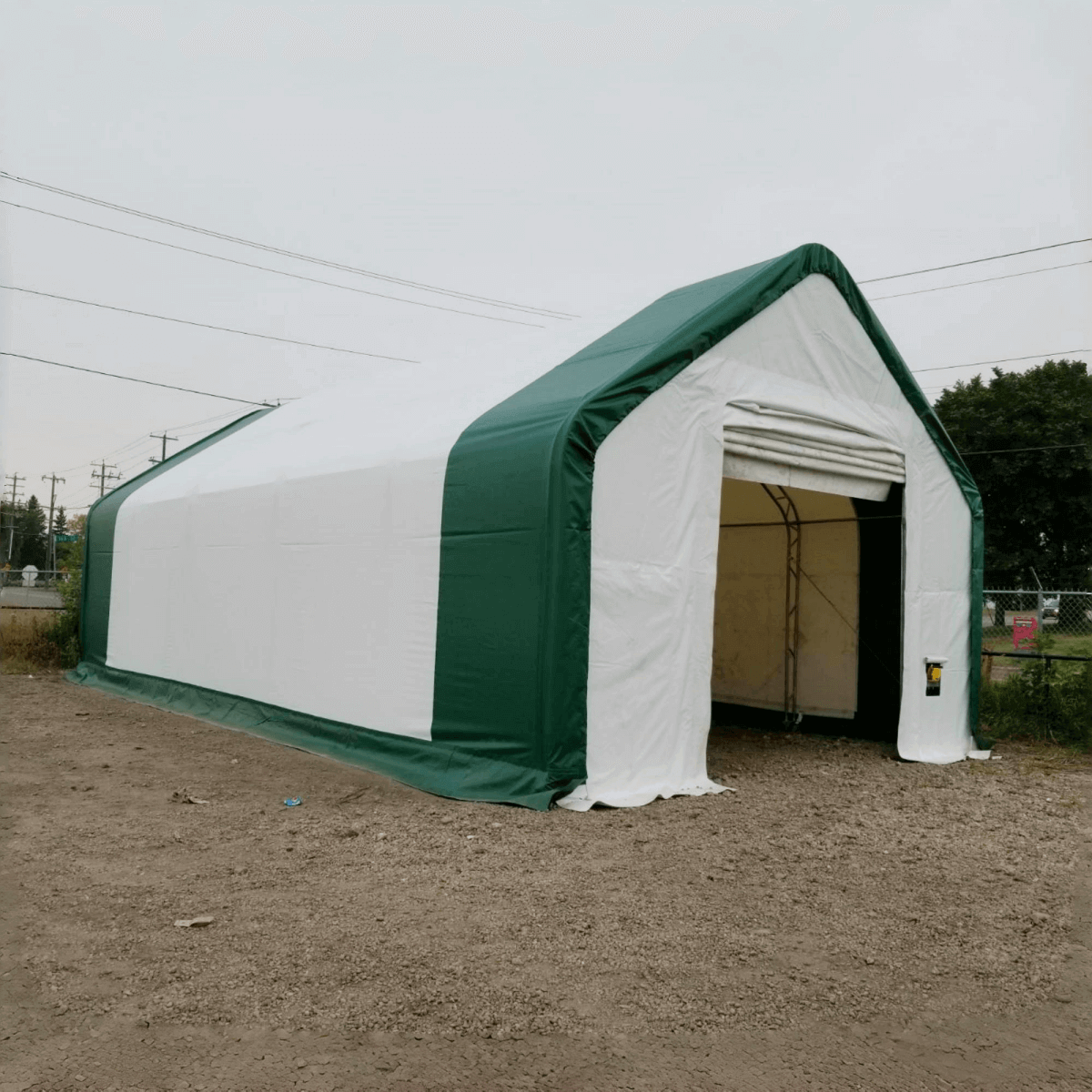 Gold Mountain storage shelter with green and white fabric, peaked roof design, open entrance