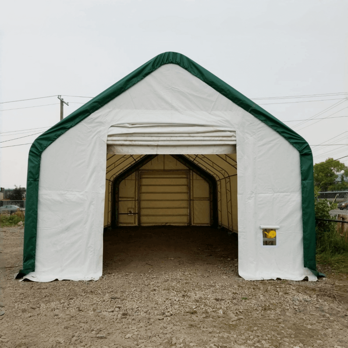 Gold Mountain storage shelter with white cover and dark green frame, open front entrance